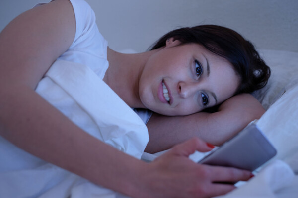 Woman texting in bed, possibly sexting