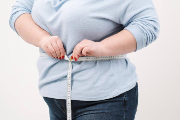 Obese, overweight woman measuring her waist size