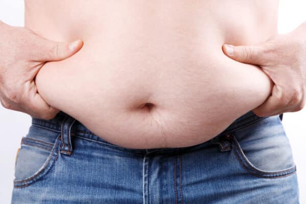 Overweight or obese man demonstrate his belly fat folds