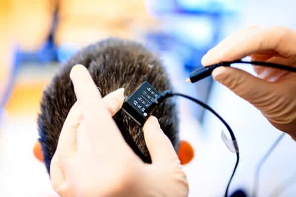 UCSF clinical research coordinator Max Dougherty connects a neural data port in Ann’s head