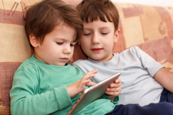 Young children playing on a tablet during screen time.