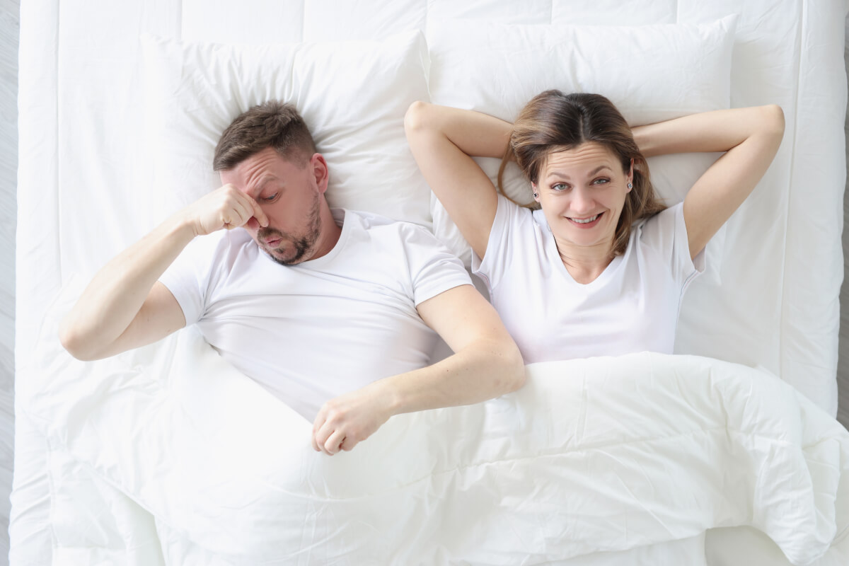 Man holding nose after woman farts in bed