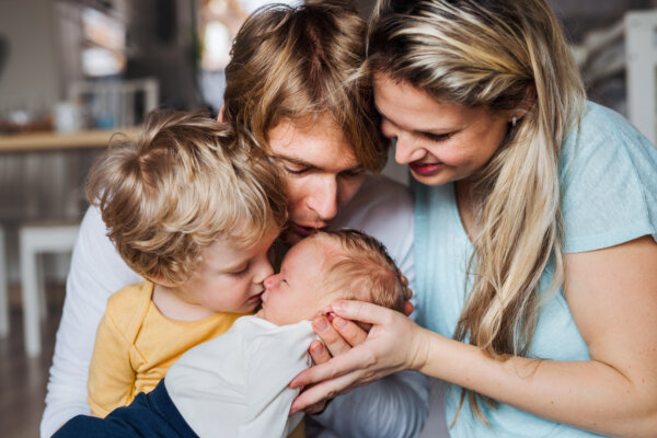 Young family kissing a newborn baby