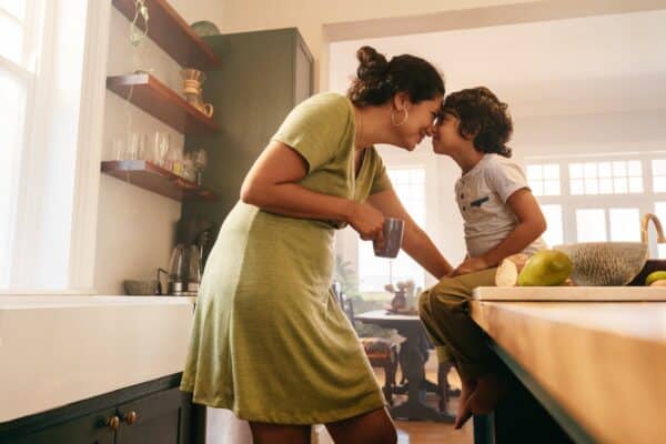 Single mother giving her son a kiss in the kitchen