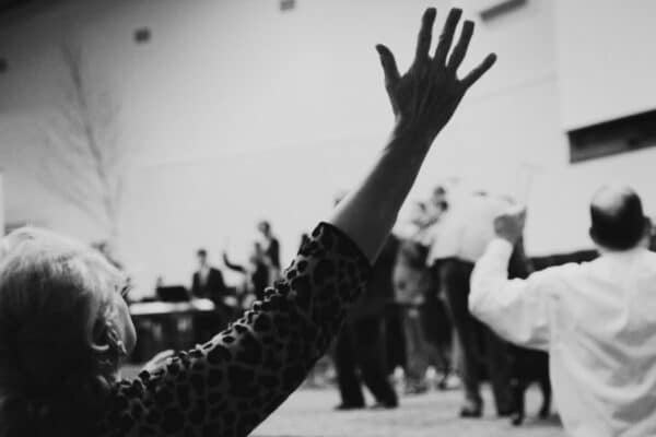 Parishioners at an apostolic pentecostal church service raise their hands in worship as their pastor preaches in tongues.