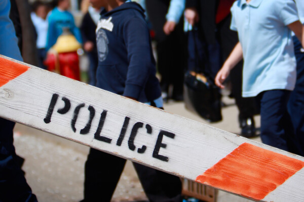 Police barricade with children in the background being evacuated.