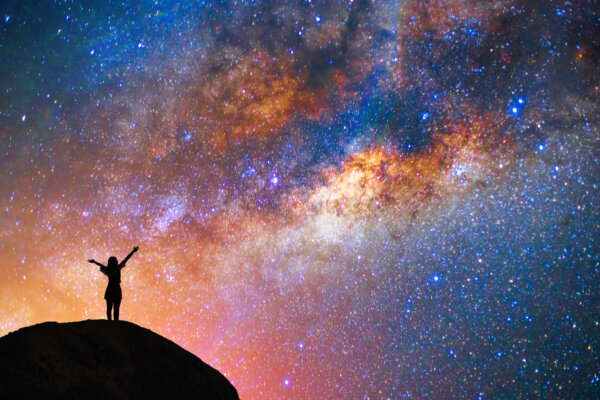Girl with arms raised at stars and planets on a beautiful night