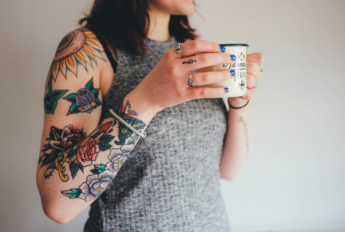 Tattooed woman holding cup of coffee