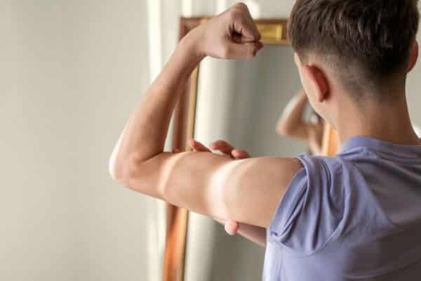 Teen boy looking at his muscles in the mirror, possible muscle or body dysmorphia
